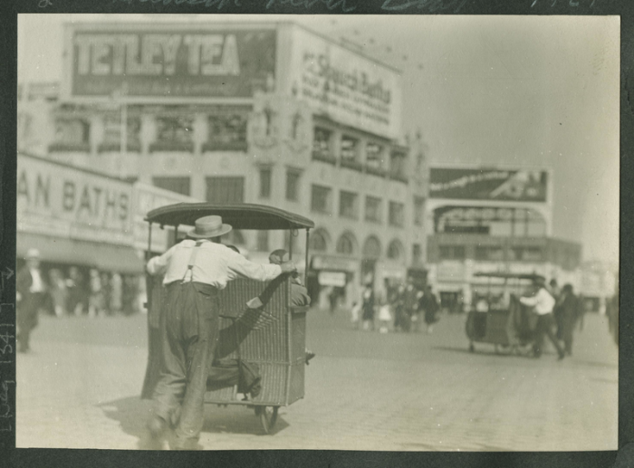 Pushing a wicker “taxi” in Coney Island, New York.